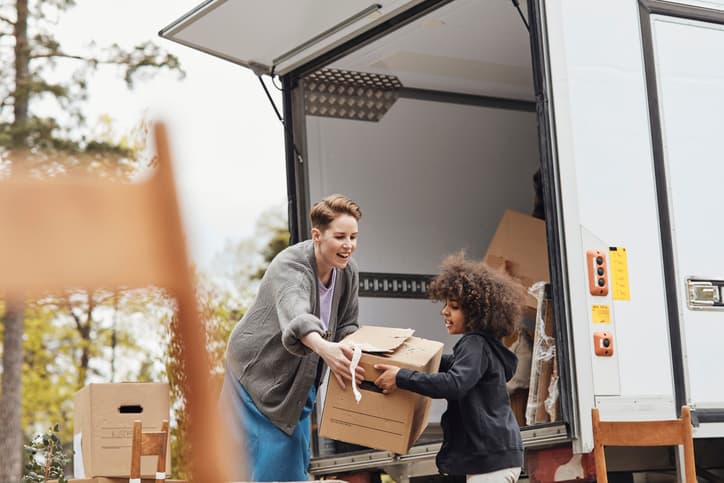 Image of a young boy helping his mother in unloading cardboard boxes from the van