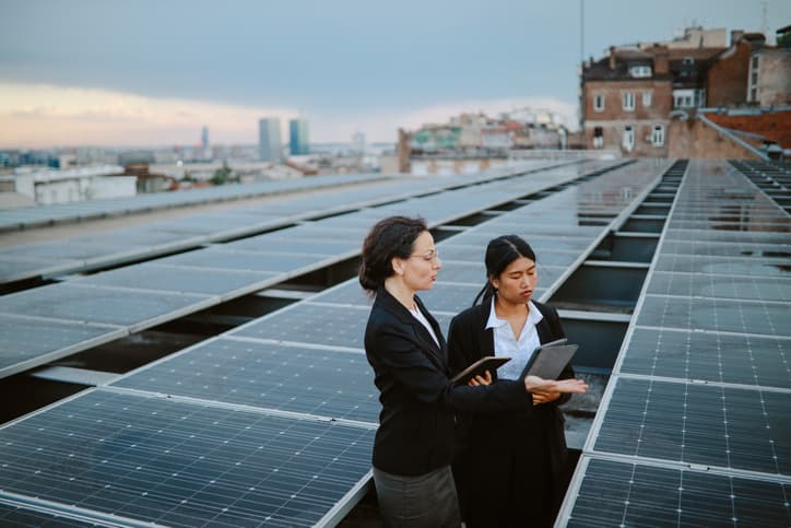 Two women holding a business meeting in front of a solar panel array